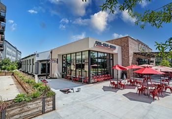 A restaurant with red chairs and umbrellas outside.